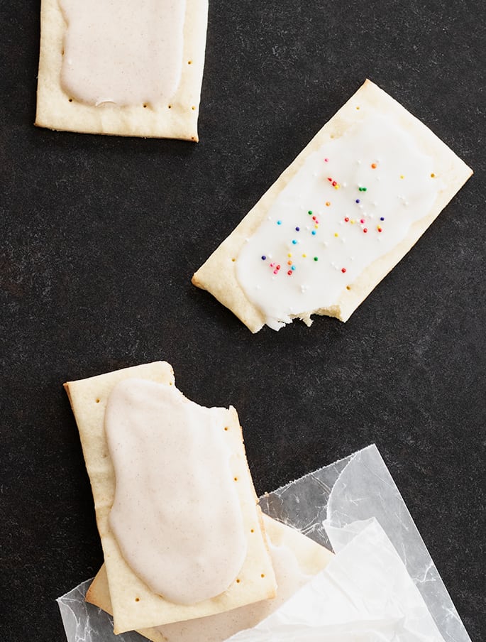 imagem de açúcar castanho e canela e tartes pop sem glúten cheias de geleia, com algumas mordidas.