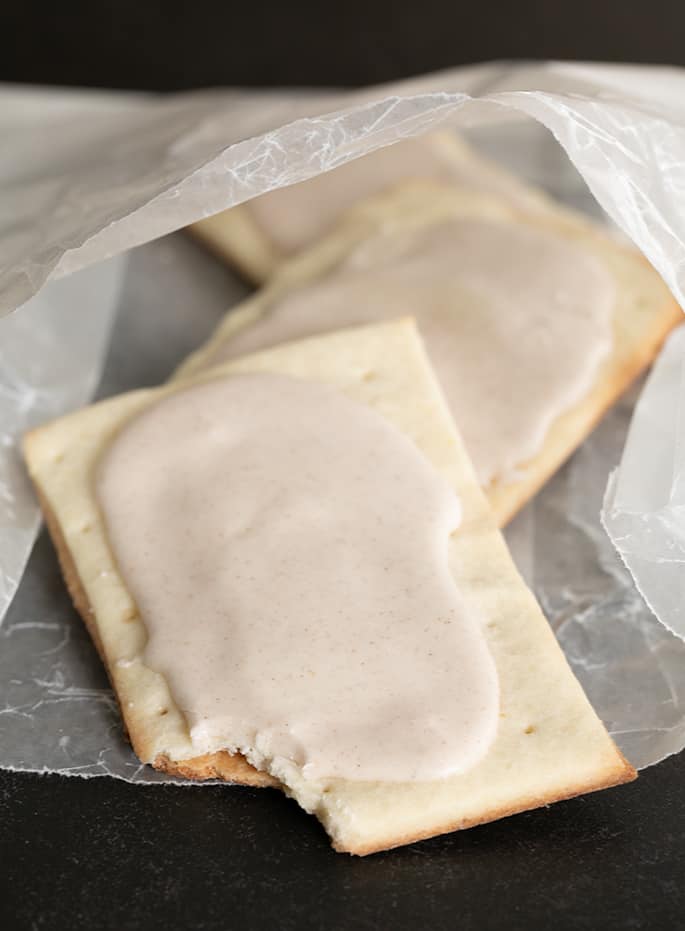 Drei glutenfreie Pop-Torten mit braunem Zucker und Zimt, eine mit einem Bissen, weil jemand nicht warten konnte.