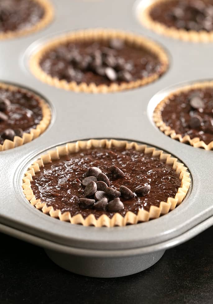 Image of raw flourless chocolate peanut butter muffin batter in muffin tin wells.