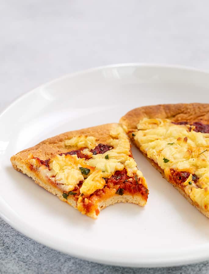 Pizza paleo dos rebanadas en un plato blanco con un bocado