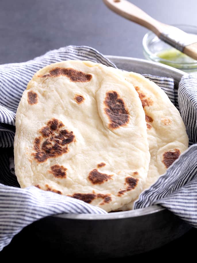 Pieces of cooked gluten free naan bread in striped cloth