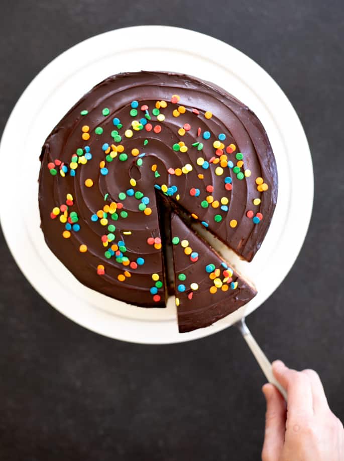 Ce gâteau d'anniversaire classique sans gluten est un gâteau à couches à la vanille funfetti rempli de glaçage à la crème aigre au chocolat et garni d'un glaçage au chocolat. C'est votre nouveau gâteau d'anniversaire à emporter.