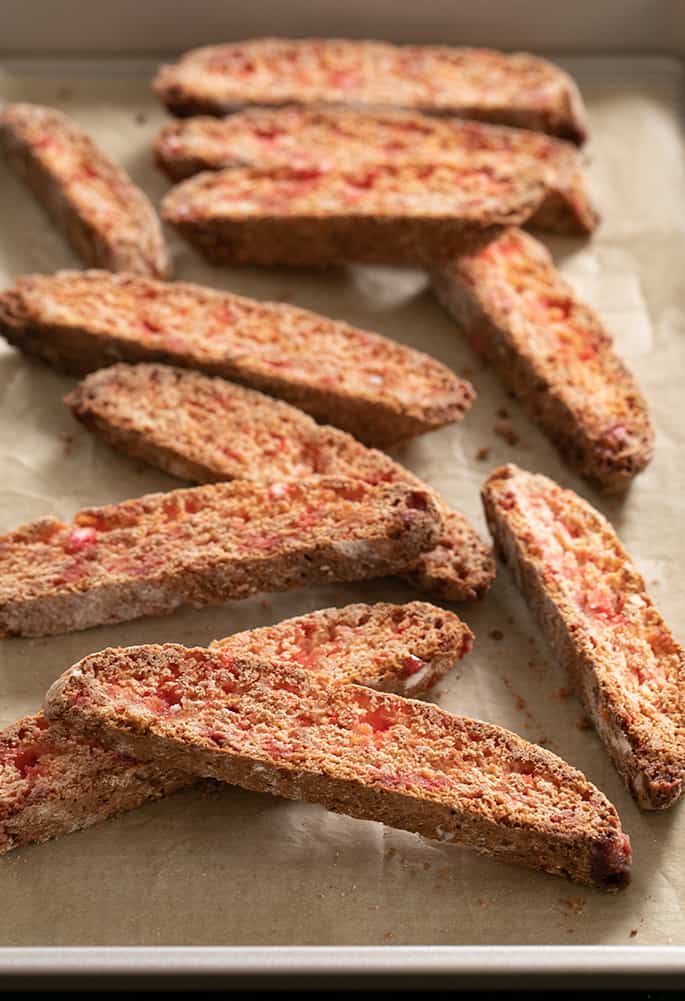 A baking sheet with fully baked candy cane gluten free biscotti.