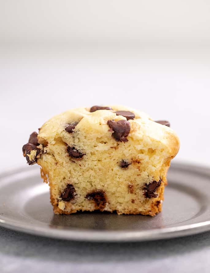 Half of a chocolate chip muffin on a small pewter plate
