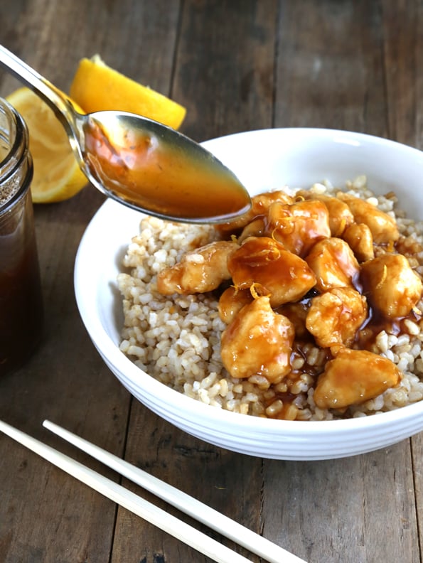 Sauce being poured onto white bowl with chicken and rice