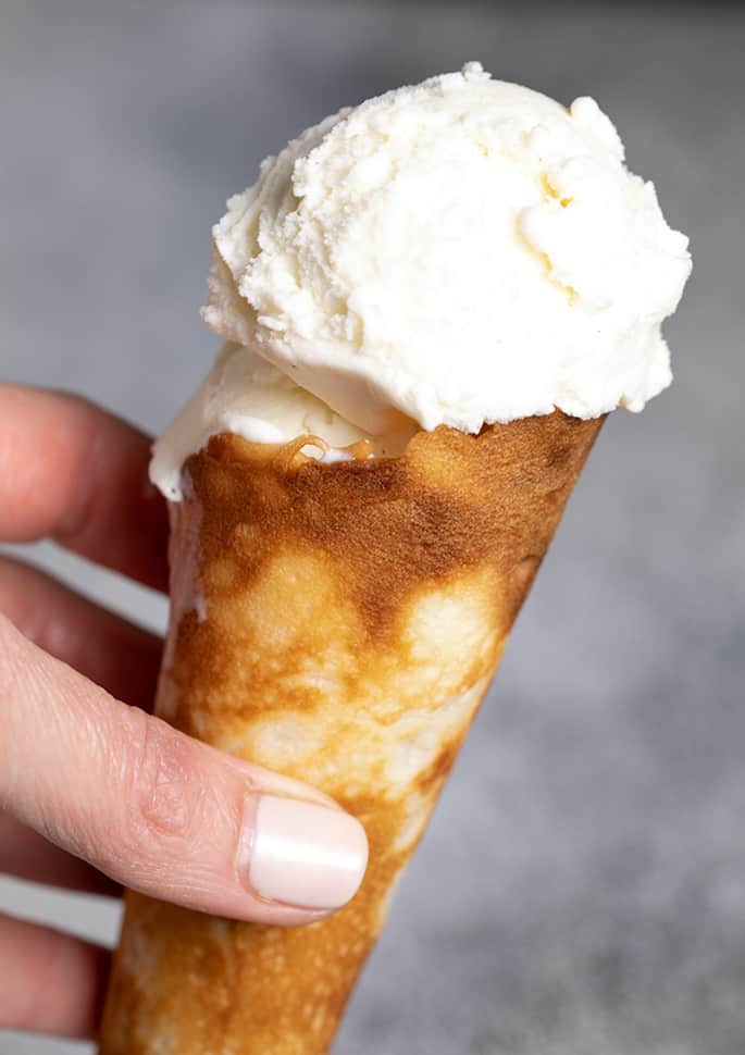 Closeup image of hand holding ice cream cone with vanilla ice cream