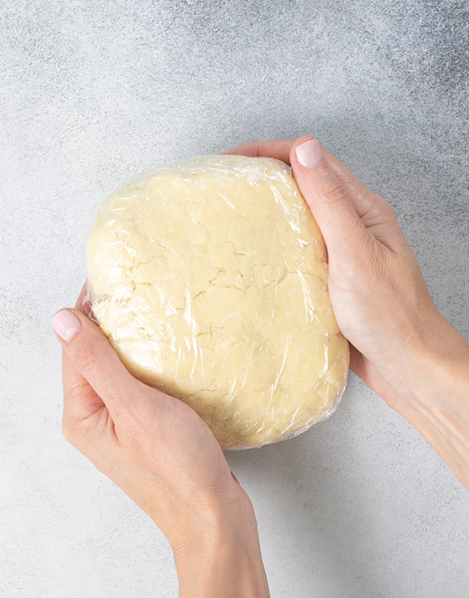 Empanada dough wrapped in plastic held in two hands