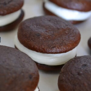 chocolate gluten free whoopie pies with white filling on white paper