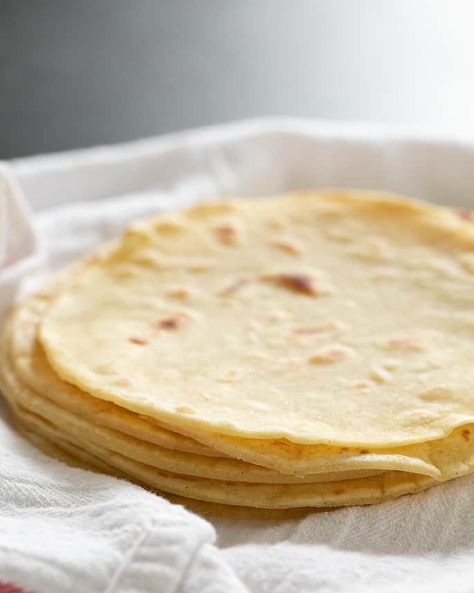 A close up of a stack of tortillas on white surface 