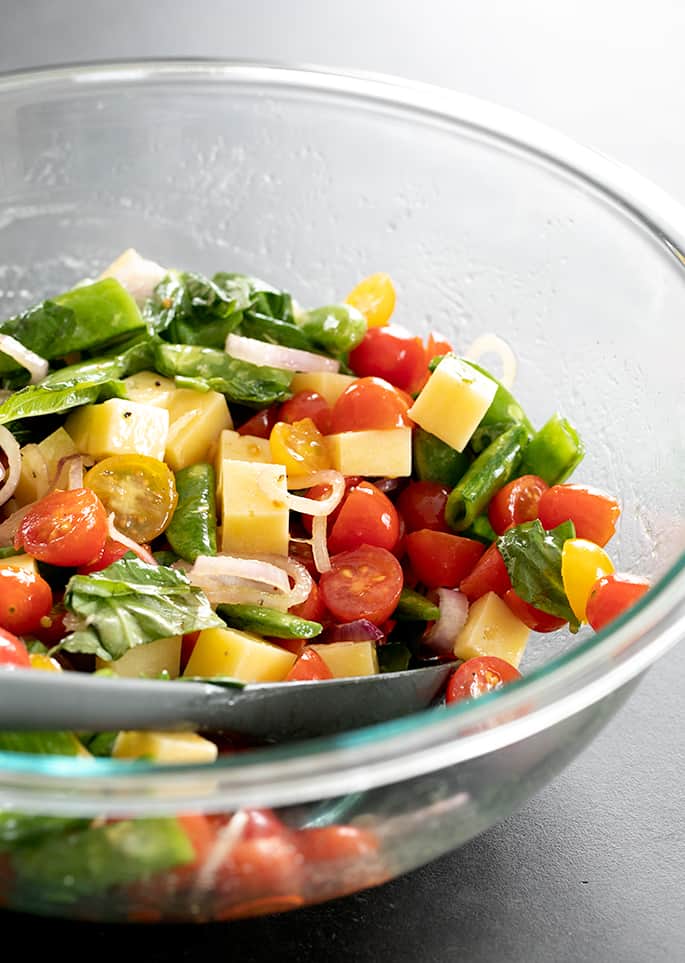 Vegetables for warm gluten free pasta salad being mixed in a serving bowl