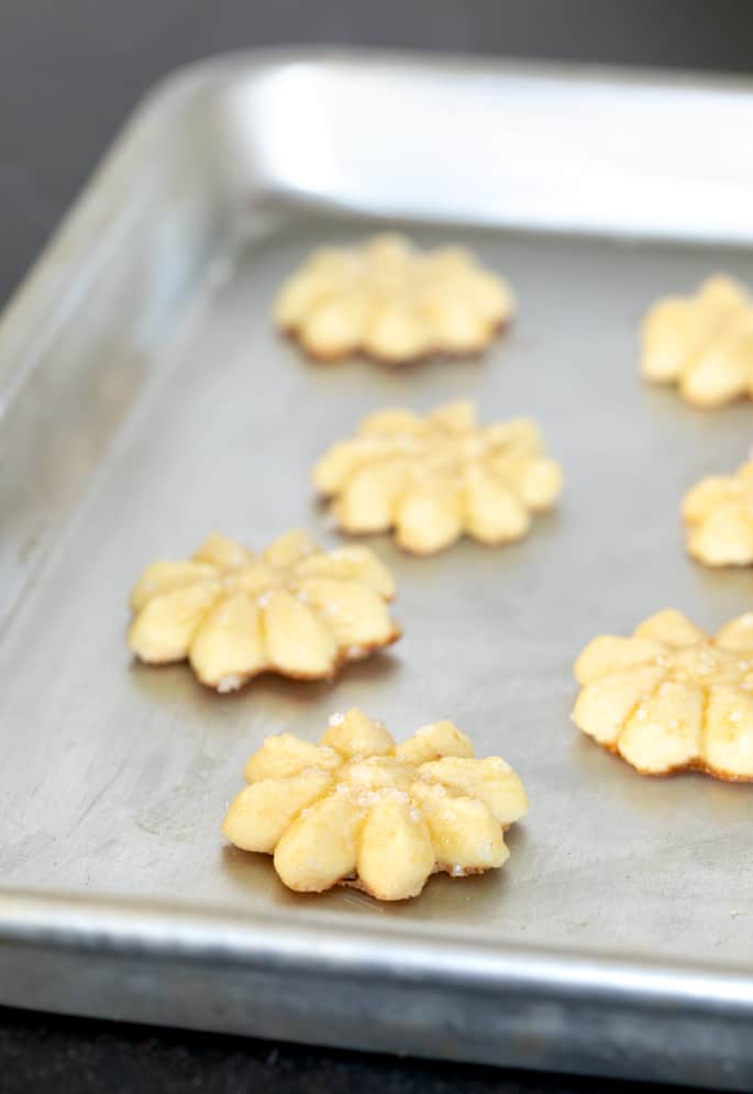 Baked gluten free butter cookies in a flower shape on a tray