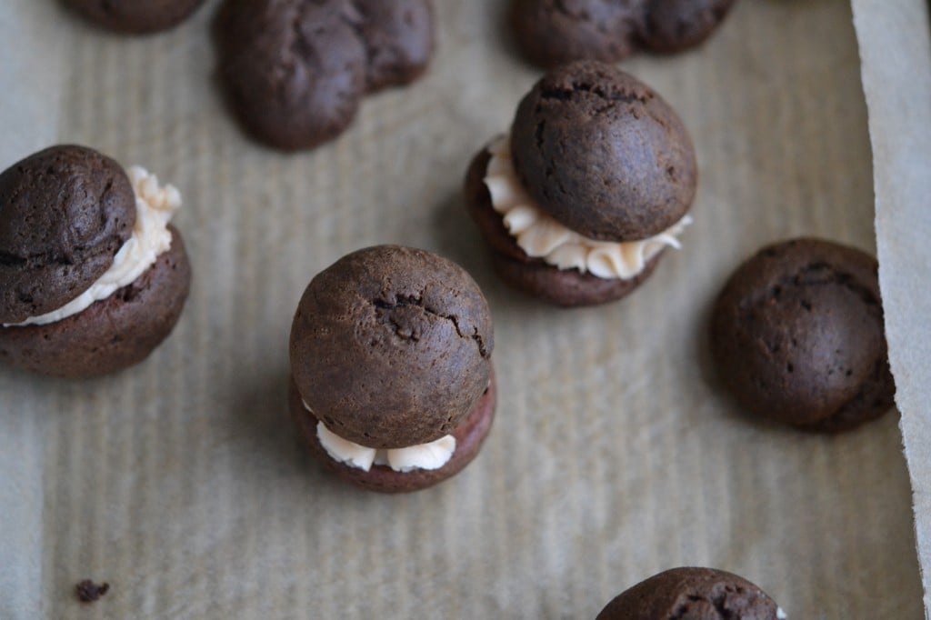 Mini Caramel Chocolate Whoopie Pies with Salted Caramel Filling on beige surface 