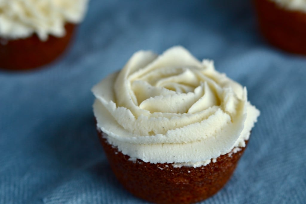 A close up of a Cupcake with white chocolate frosting on blue surface 