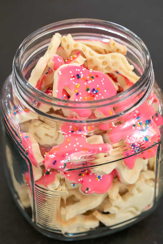 Glass jar filled with animal crackers some with frosting and nonpareils