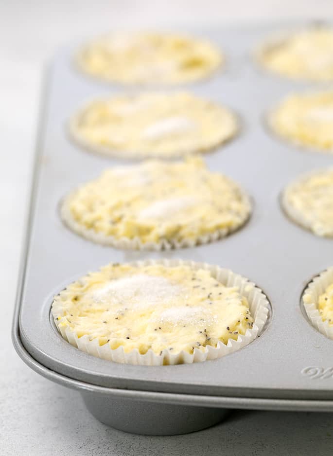 Raw lemon poppyseed muffin batter in muffin tin wells