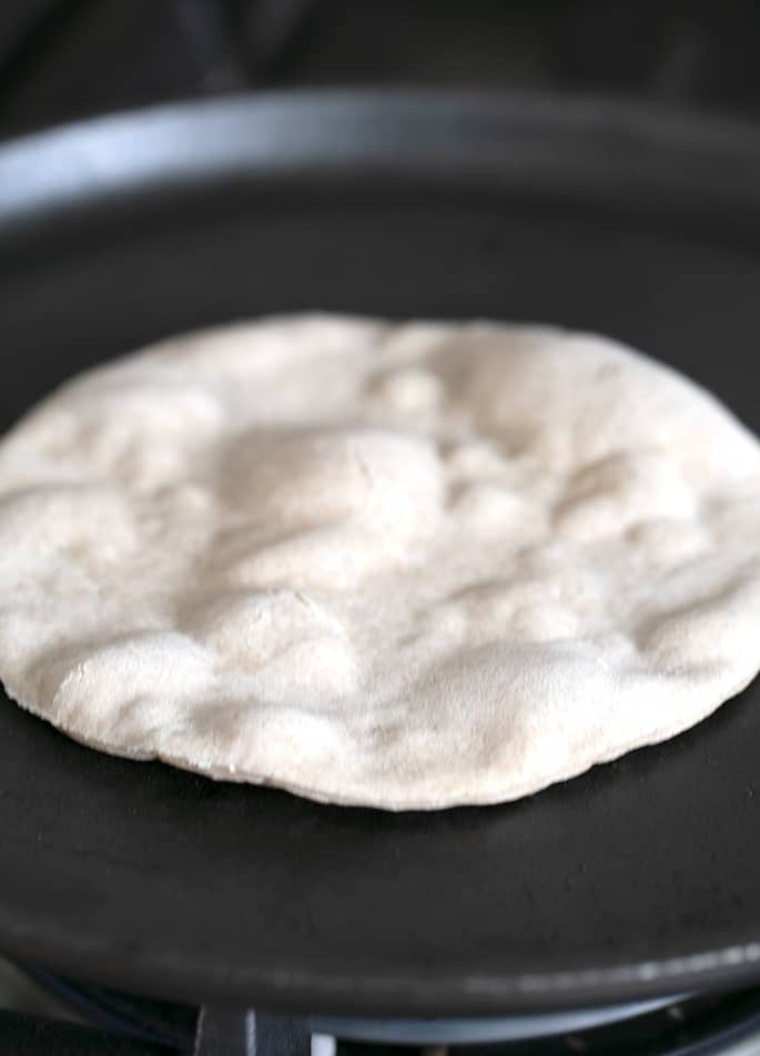 Tortilla being cooked on black pan