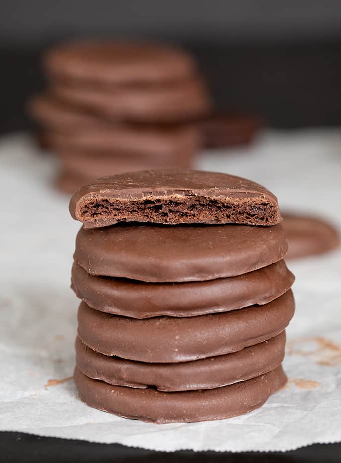 A short stack of gluten free thin mints cookies with the top one broken to show the inside.