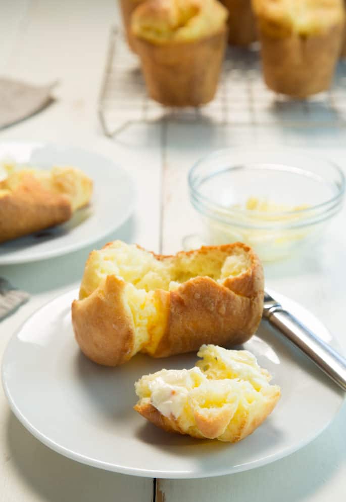 Inside of popper with butter inside on a white plate with a knife