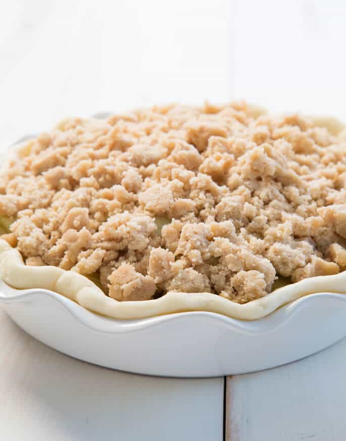 Dutch apple pie in white baking tray on white surface