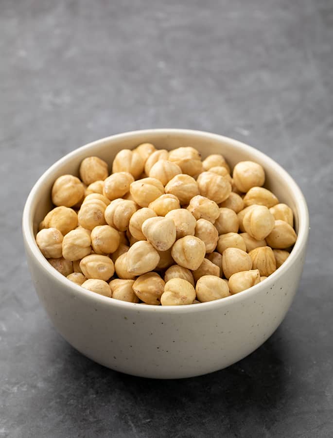 Blanched whole hazelnuts in small white bowl