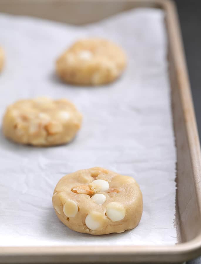 Raw cookie dough disks on white paper on a tray