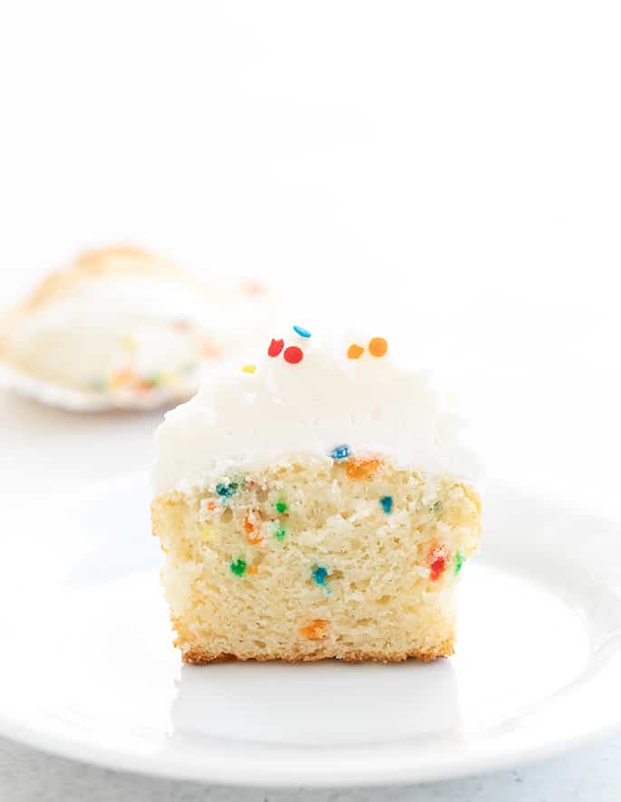 Gluten free Funfetti cupcake on a plate sliced in half