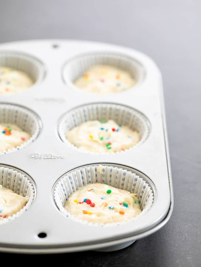 Gluten free funfetti cupcake batter raw in wells of muffin tin