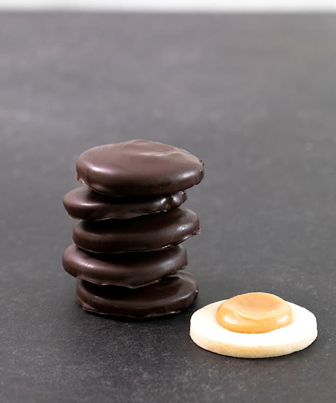 A stack of chocolate covered tagalongs with one cookie without chocolate