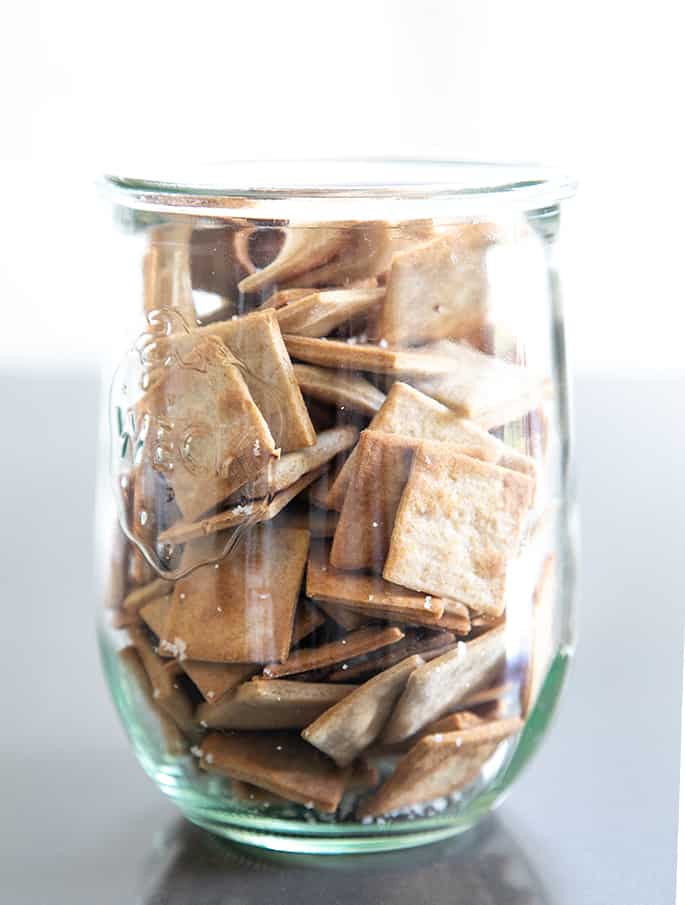 A clear glass jar with gluten free wheat thins style crackers