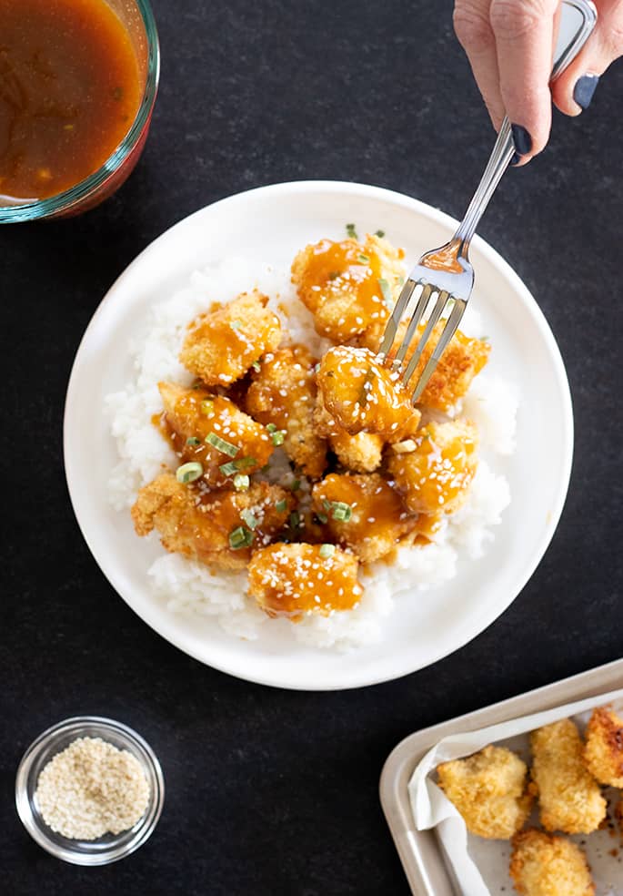 Gluten free sesame chicken overhead being served and eaten.