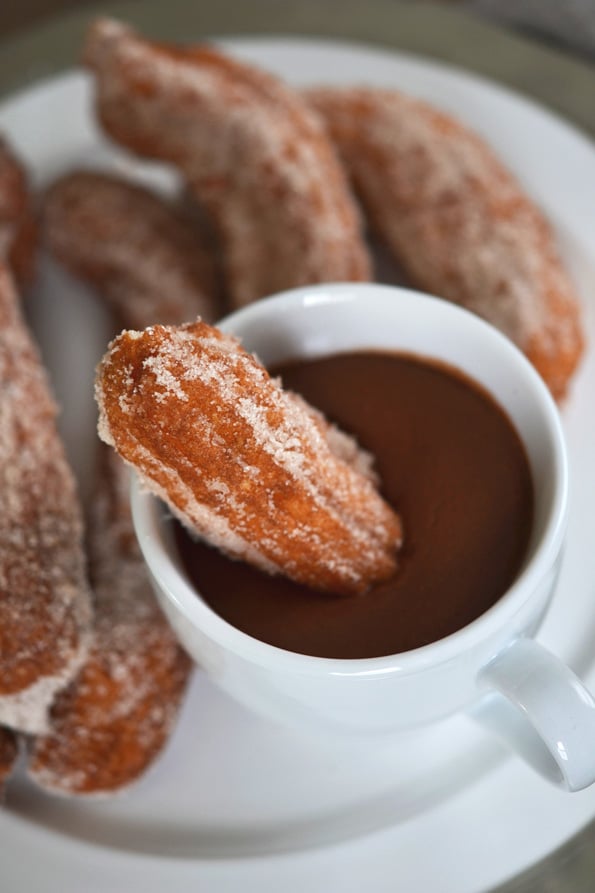 A close up churros being dipped in chocolate sauce 