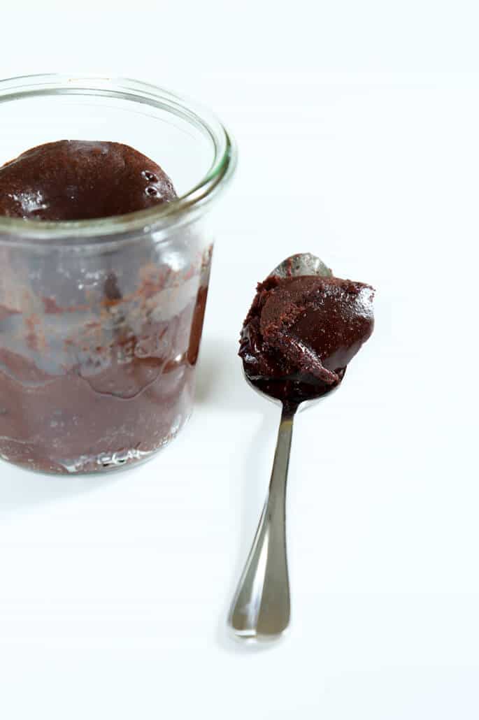 A small mason jar with chocolate cake and a spoonful of cake.