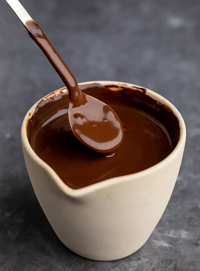 Chocolate sauce in ceramin pouring jar with long metal spoon