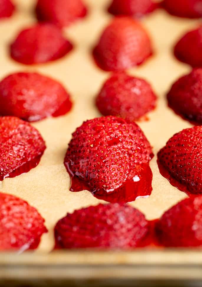 Strawberry halves roasted on brown paper on baking sheet