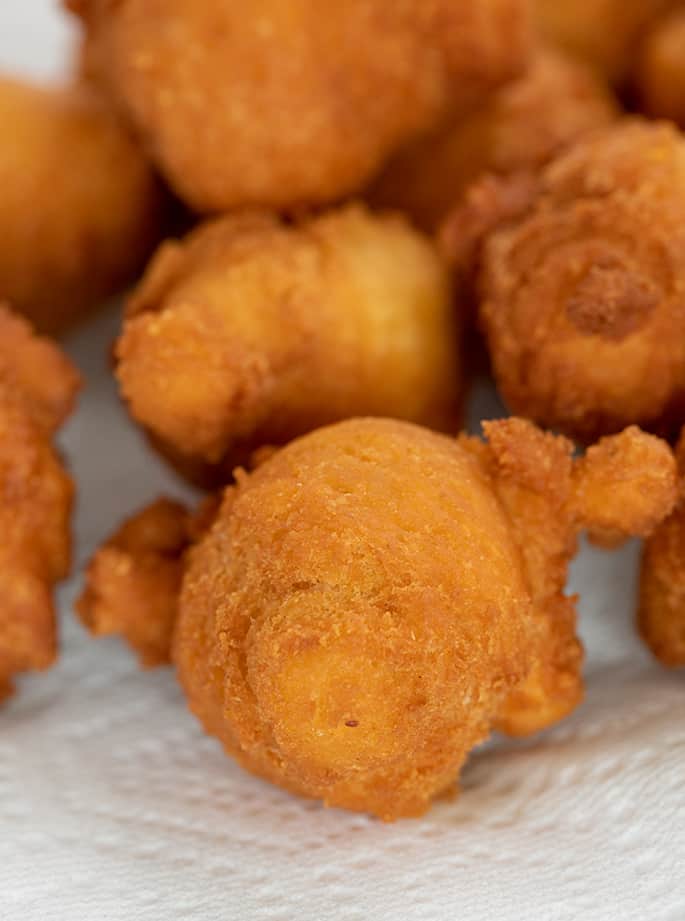 closeup of irregularly shaped fritters on white paper towel