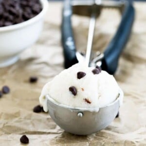 Dairy free ice cream in ice cream scoop with chocolate chips on beige paper