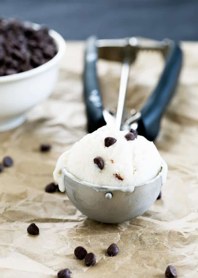 Dairy free ice cream in ice cream scoop with chocolate chips on beige paper