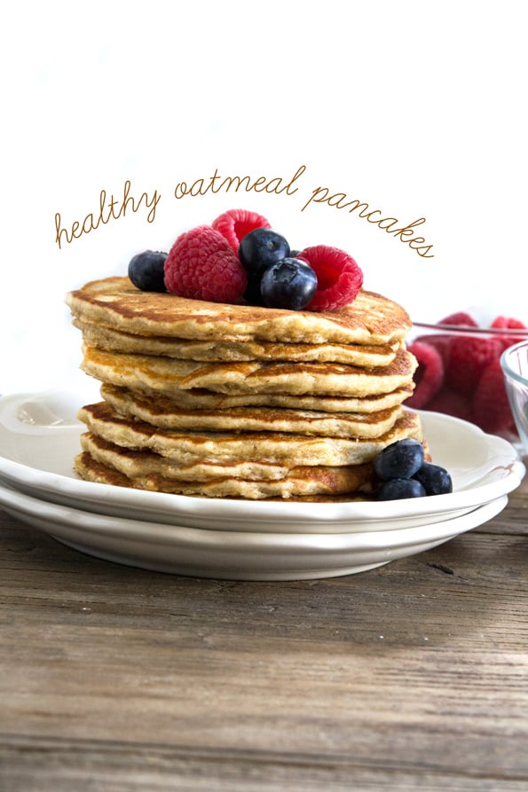 Stack of pancakes with fruit on top of a wooden table