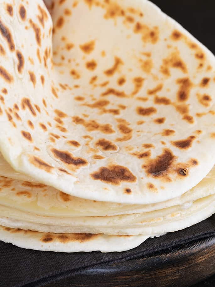 A close up of a stack of soft tapioca wraps, one being bent.