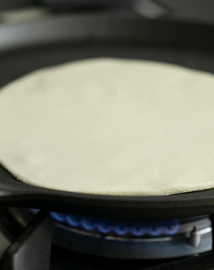 Raw soft tapioca wrap being cooked in a pan