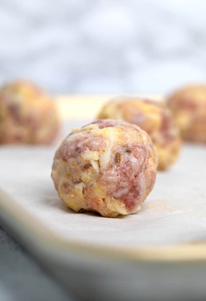 Closeup image of raw sausage ball on white paper on tray