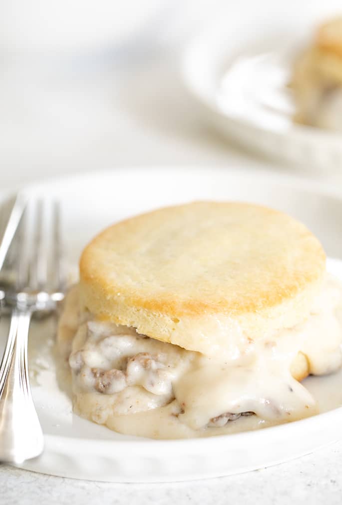 Sausage gravy on a biscuit on a plate with a fork closeup image