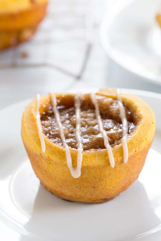 A close up of a pumpkin cinnamon roll on a white plate 