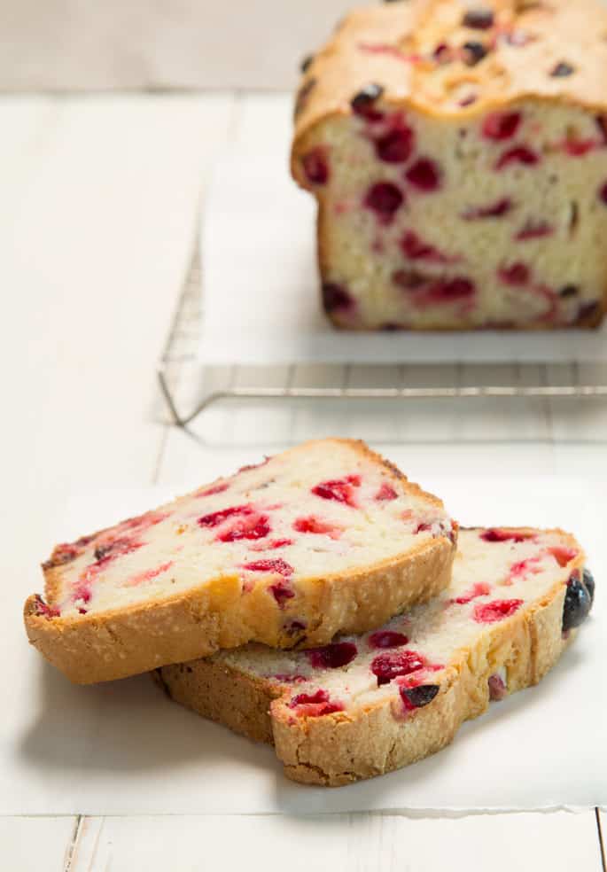 A close up of 2 slices of cranberry bread on a white background 