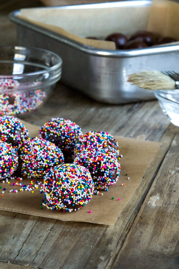 A bunch of fudge truffles with nonpareils on paper on a table