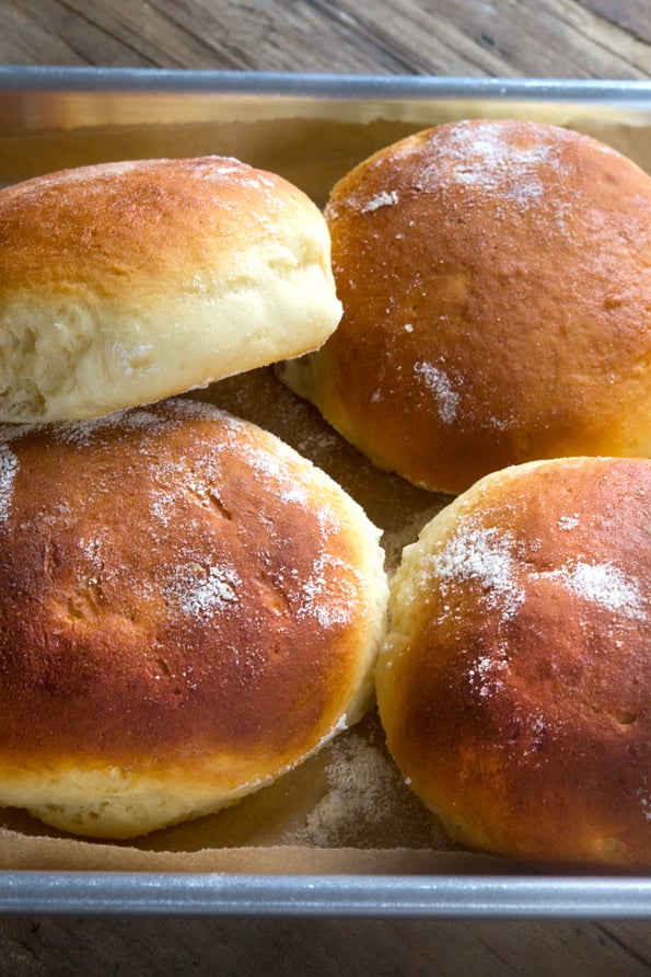 A close up of a gluten free Hawaiian bread rolls in a pile on a tray.