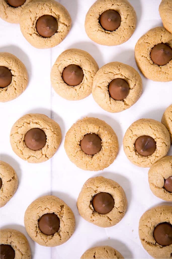 Birds eye view of peanut butter blossom cookies on white surface