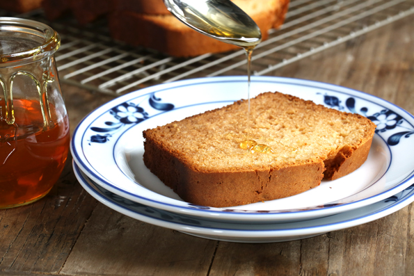 honey being drizzled on bread on white plate 