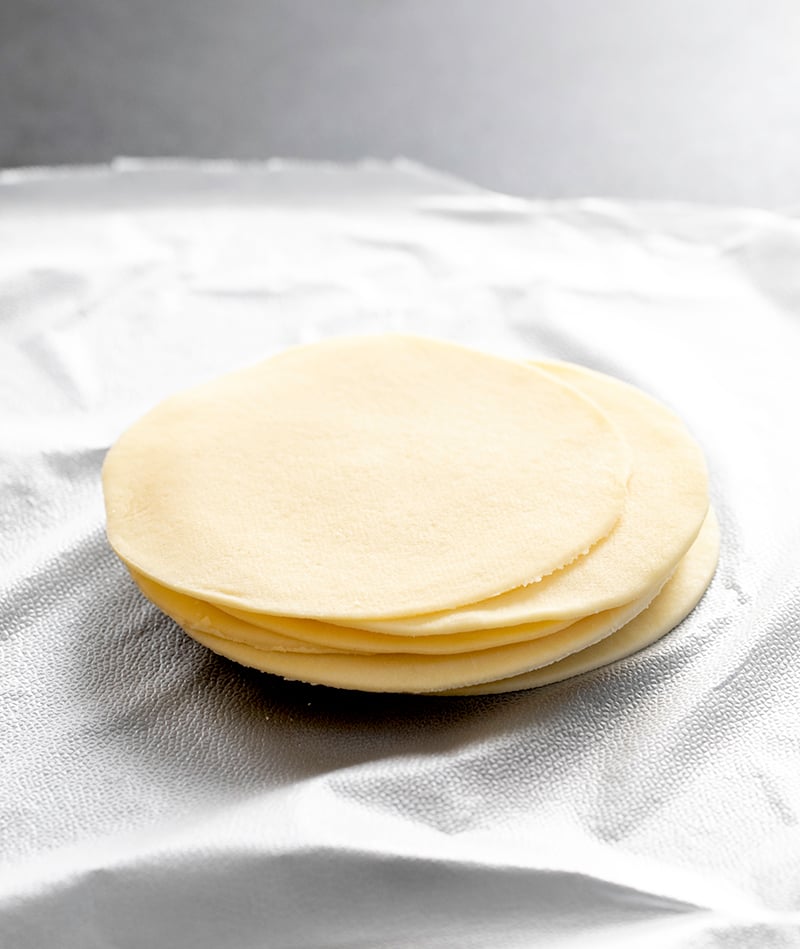 Stack of round gluten free won ton wrappers on unwrapped plastic wrap