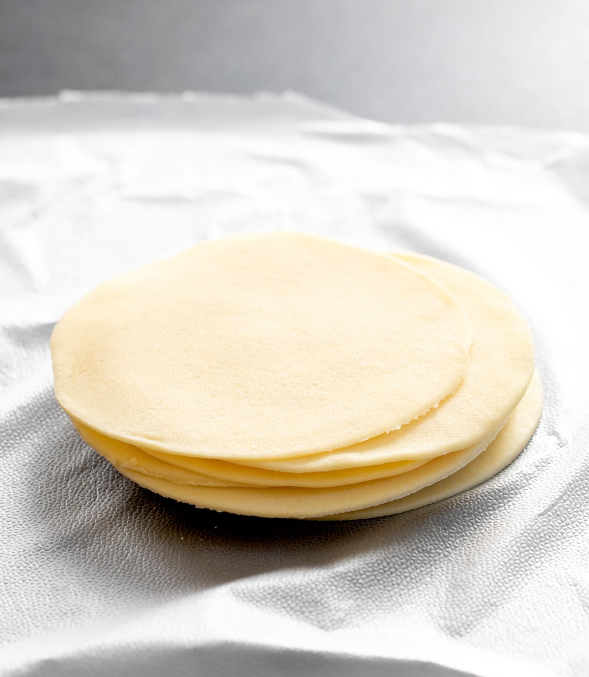Stack of round gluten free won ton wrappers on unwrapped plastic wrap
